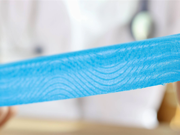 Ergotherapeutin legt Kinesio-Tape am Handgelenk und an den Fingern einer Patientin in der Handrehabilitation an